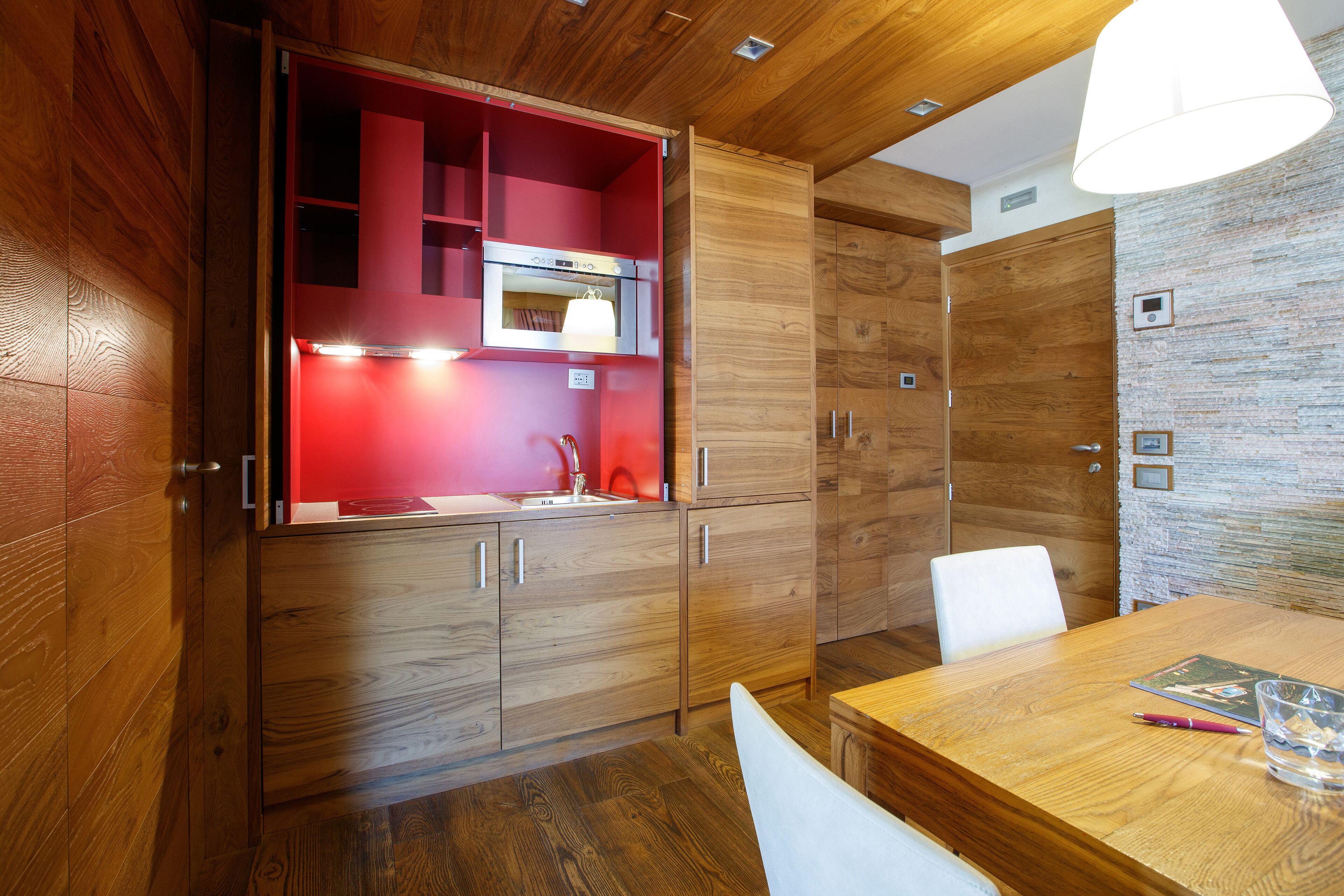 Een moderne keuken met houten kastjes, een rode spatwand en een inbouwoven.