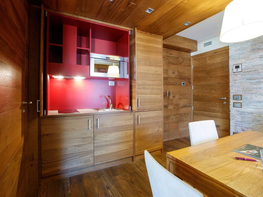 Una cocina moderna con armarios de madera, un salpicadero rojo y un horno empotrado.