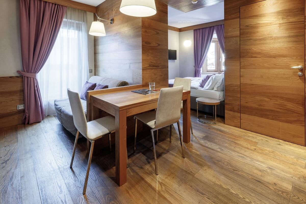 Una habitación moderna con una mesa de comedor de madera, sillas, un sofá y una cama.