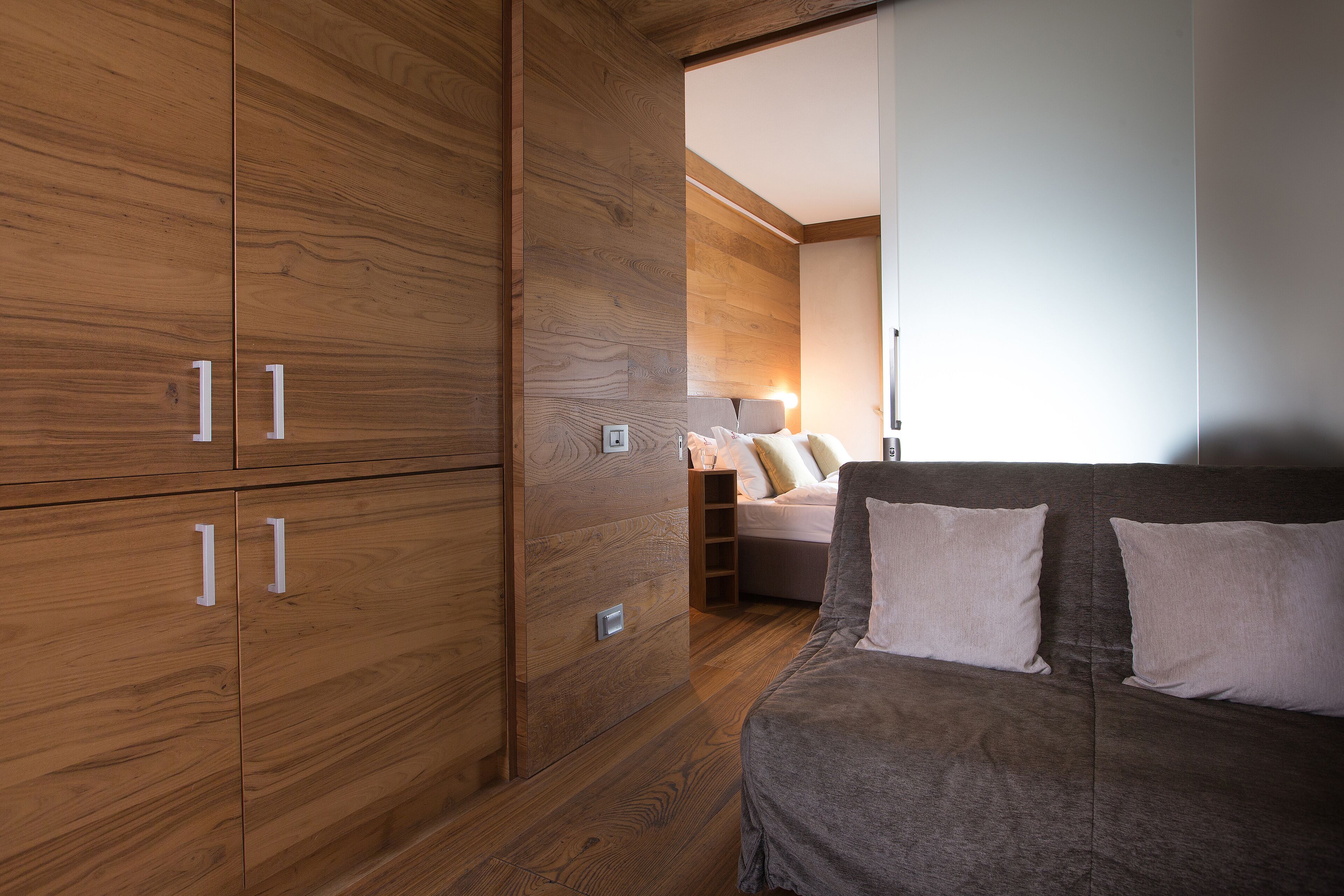 Une chambre avec une armoire en bois, un lit avec des oreillers et une table de chevet.