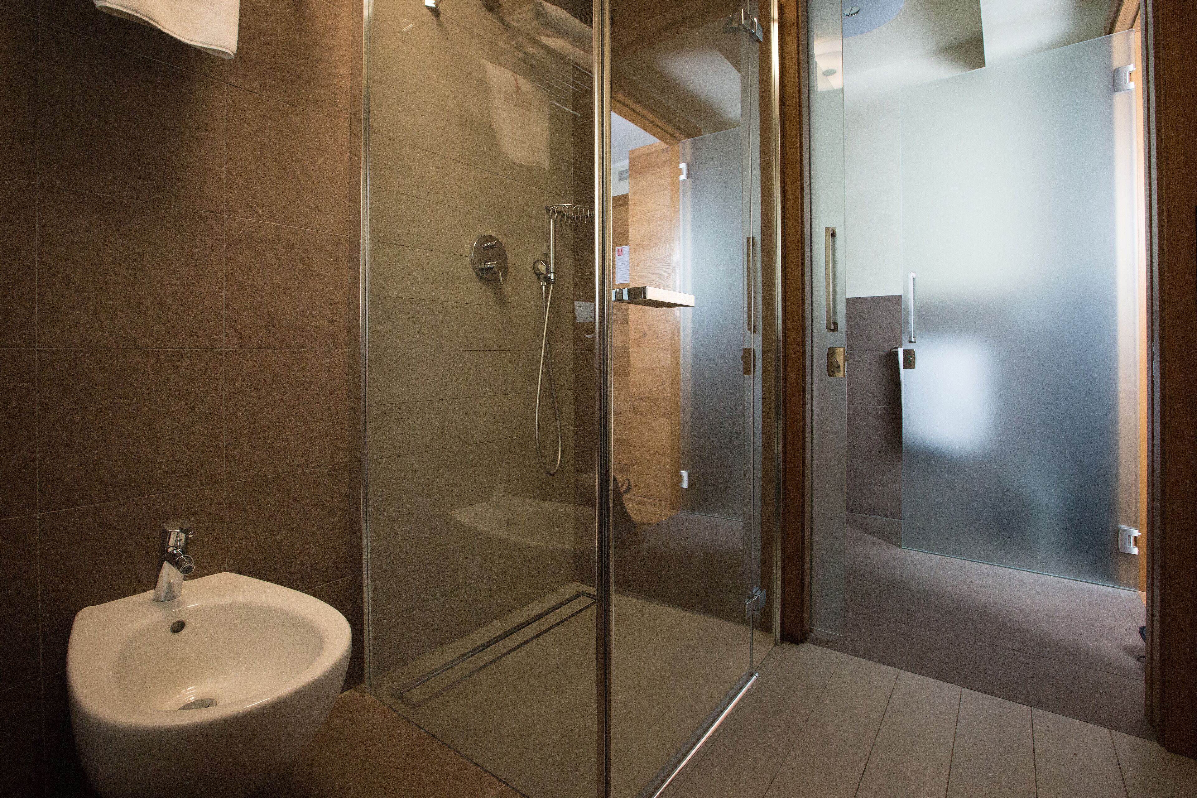 A modern bathroom with a glass-enclosed shower, a white sink, and a wooden vanity.