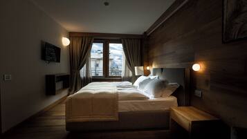 Ein Schlafzimmer mit einem großen Bett, Holzwänden, einem Fenster mit Vorhängen und Nachttischlampen.