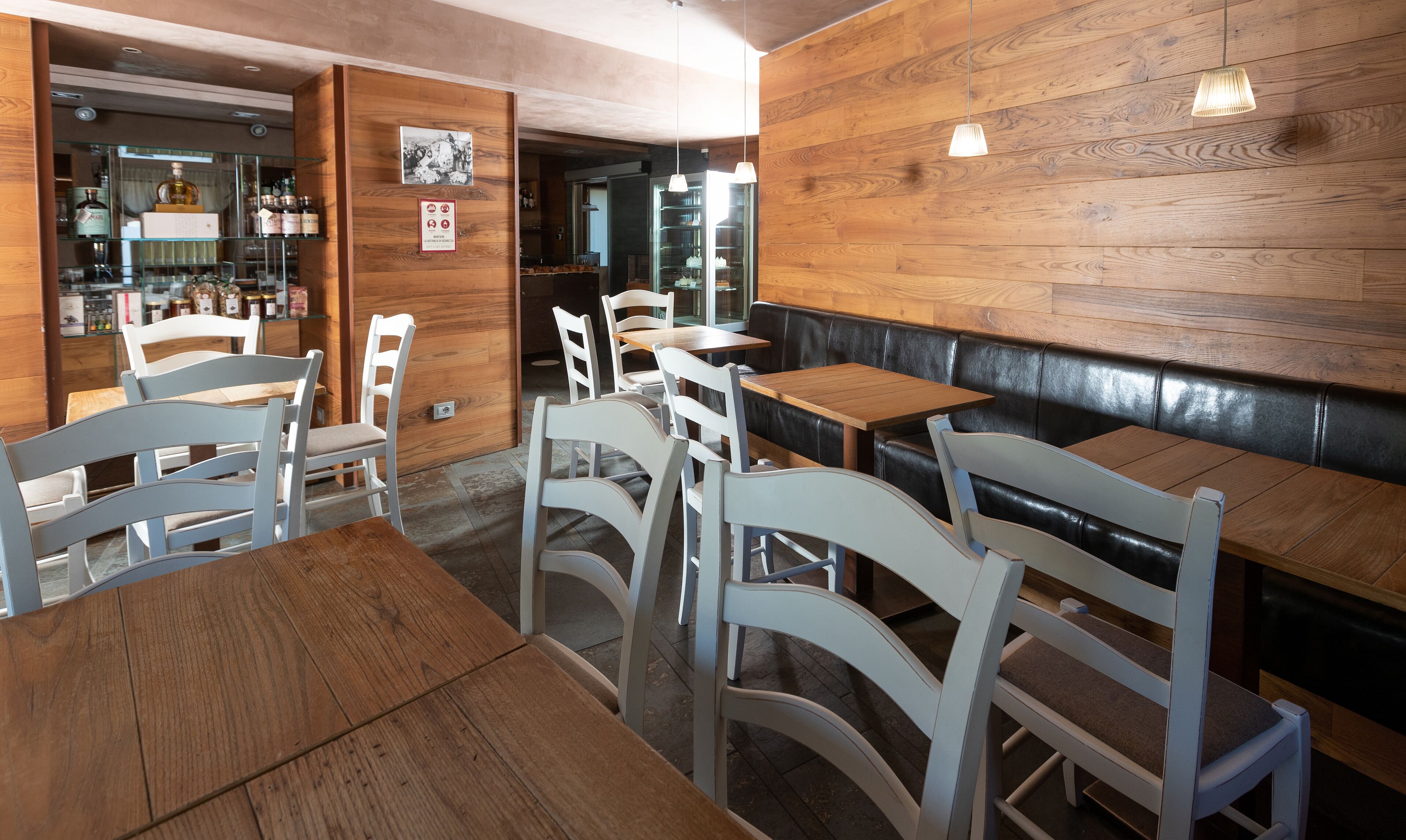 A restaurant interior with wooden walls, white chairs, and tables.