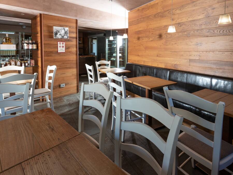 A restaurant interior with wooden walls, white chairs, and tables.