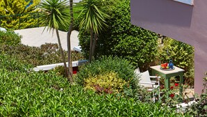 A coastal view with a balcony, greenery, and a table with a vase of flowers. - Everest Apartments (Hersonissos)