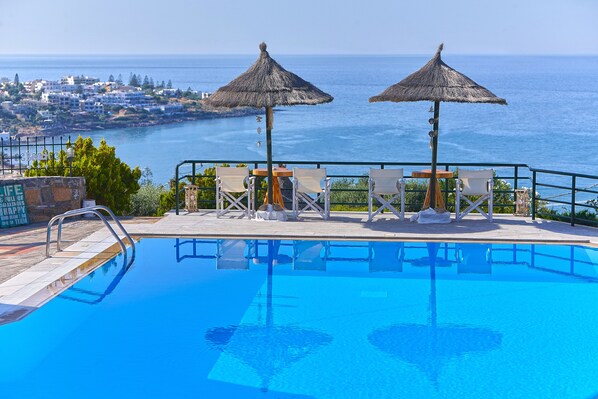 Una piscina al aire libre, sombrillas, sillones reclinables de piscina