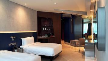 Habitació d'hotel moderna amb dos llits, zona de seients i barra minibar.