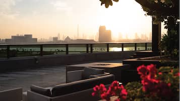 A rooftop terrace with outdoor seating and a view of a city skyline.