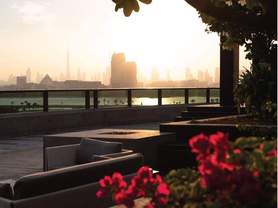A rooftop terrace with outdoor seating and a view of a city skyline.