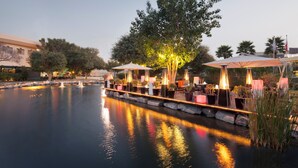 A serene riverside setting with outdoor seating areas and illuminated lamps. - The Creekside Hotel Dubai an Accor Hotel (Dubai)