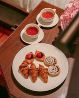 A breakfast tray with croissants, a rolled pastry, and a cup of tea on a wooden table.