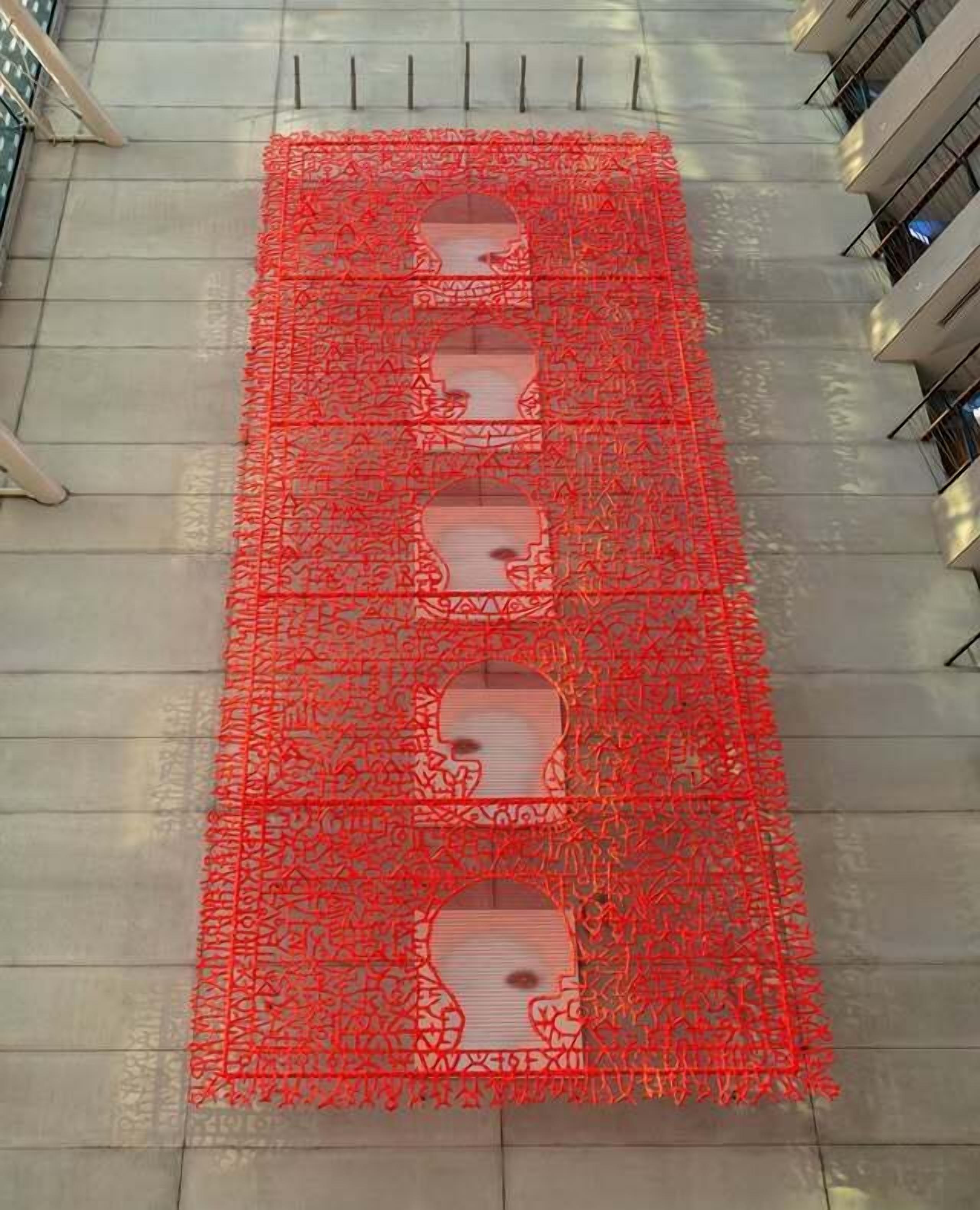 Un motif géométrique rouge orne la façade d’un immeuble.
