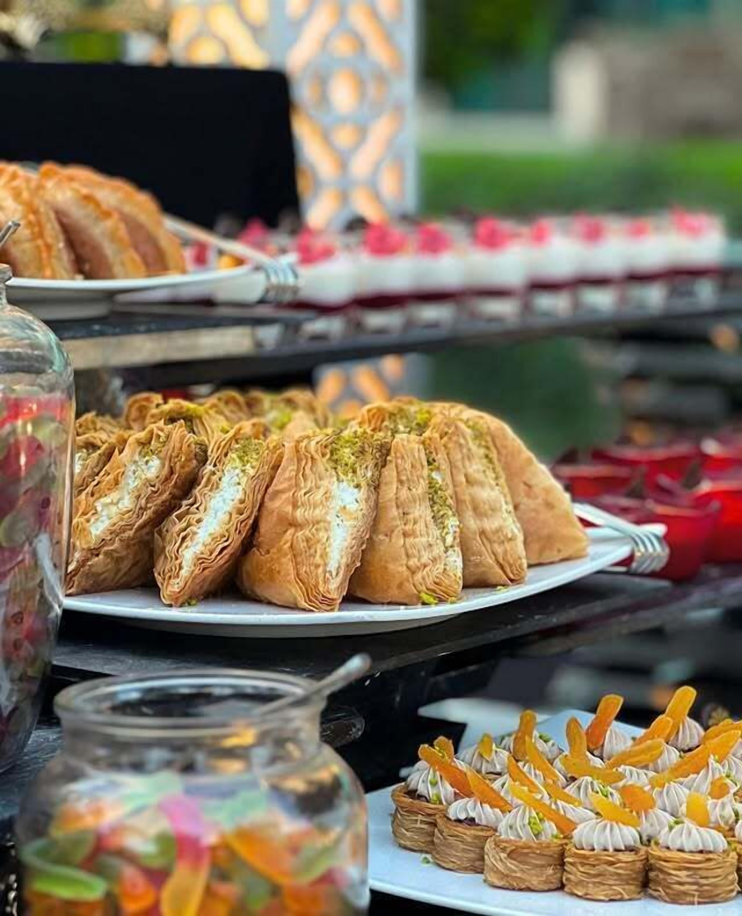 Una mesa con diversos pasteles, incluyendo baklava y otras delicias dulces, exhibida en un mercado.