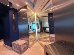 Une chambre d’hôtel moderne avec un grand miroir, un mur décoratif en marbre et un lit doté d’une tête de lit.