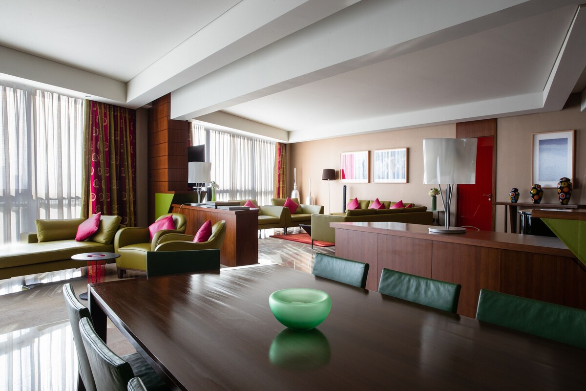 Une chambre d’hôtel moderne comprenant un coin repas, un ensemble de canapés et un coin cuisine.
