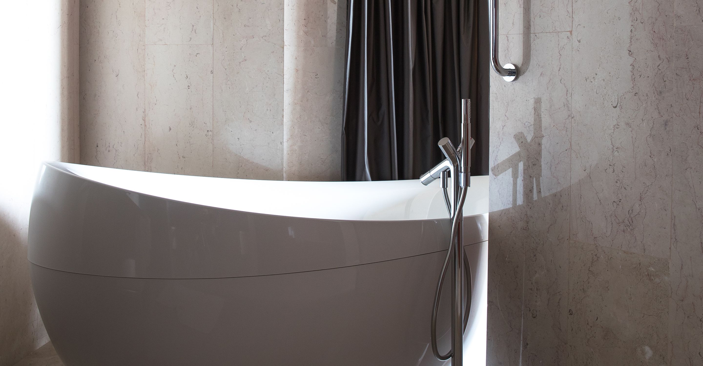 A modern bathroom with a white bathtub, a chrome faucet, and a shower head.