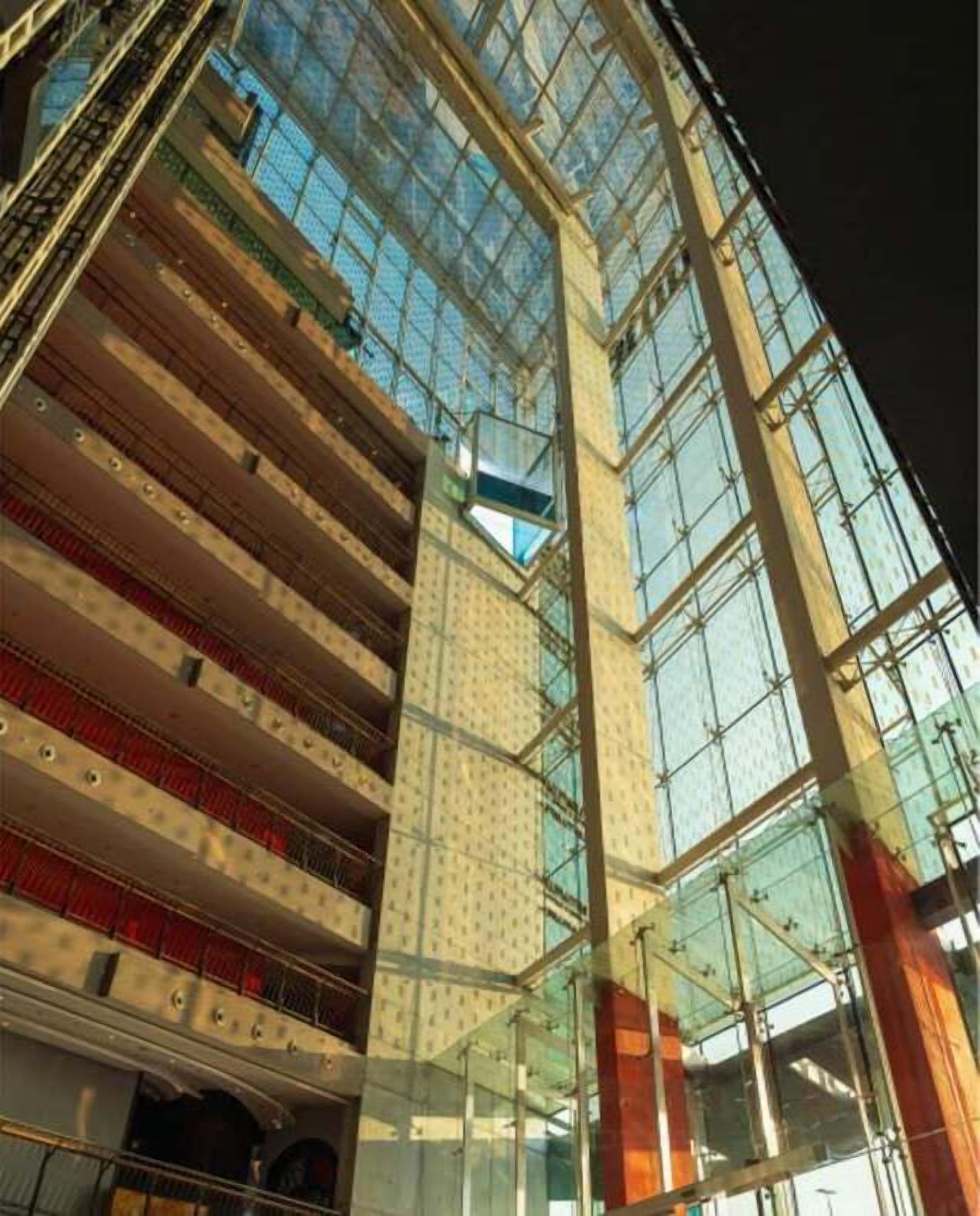 Un immeuble à plusieurs étages doté d’une façade en verre et d’un escalier apparent.