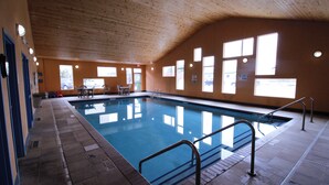 An indoor swimming pool with clear blue water, surrounded by tiled walls and a wooden ceiling. - Canby Inn And Suites (Canby)