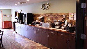 A modern kitchen with a 'Eat' sign, stainless steel appliances, and a coffee station. - Canby Inn And Suites (Canby)