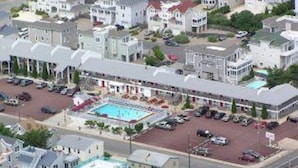 A multi-story hotel with a swimming pool, parking lot, and several buildings with similar architecture. - Sea Spray Motel (Beach Haven)