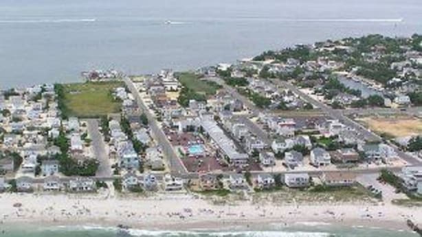 An aerial view of a coastal residential area with houses, a beach, and a marina. - Sea Spray Motel (Beach Haven)