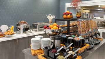 Um buffet com diversos alimentos, incluindo frutas, cereais e doces.