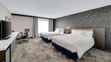 Ein Hotelzimmer mit zwei Betten, einem Schreibtisch, einem Stuhl und einem Fernseher.