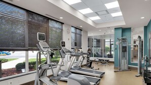 A modern gym with treadmills, elliptical machines, and weight equipment.