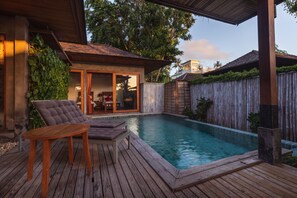 Um deck de madeira com piscina, cadeiras de descanso e porta de vidro que dá para um quarto.