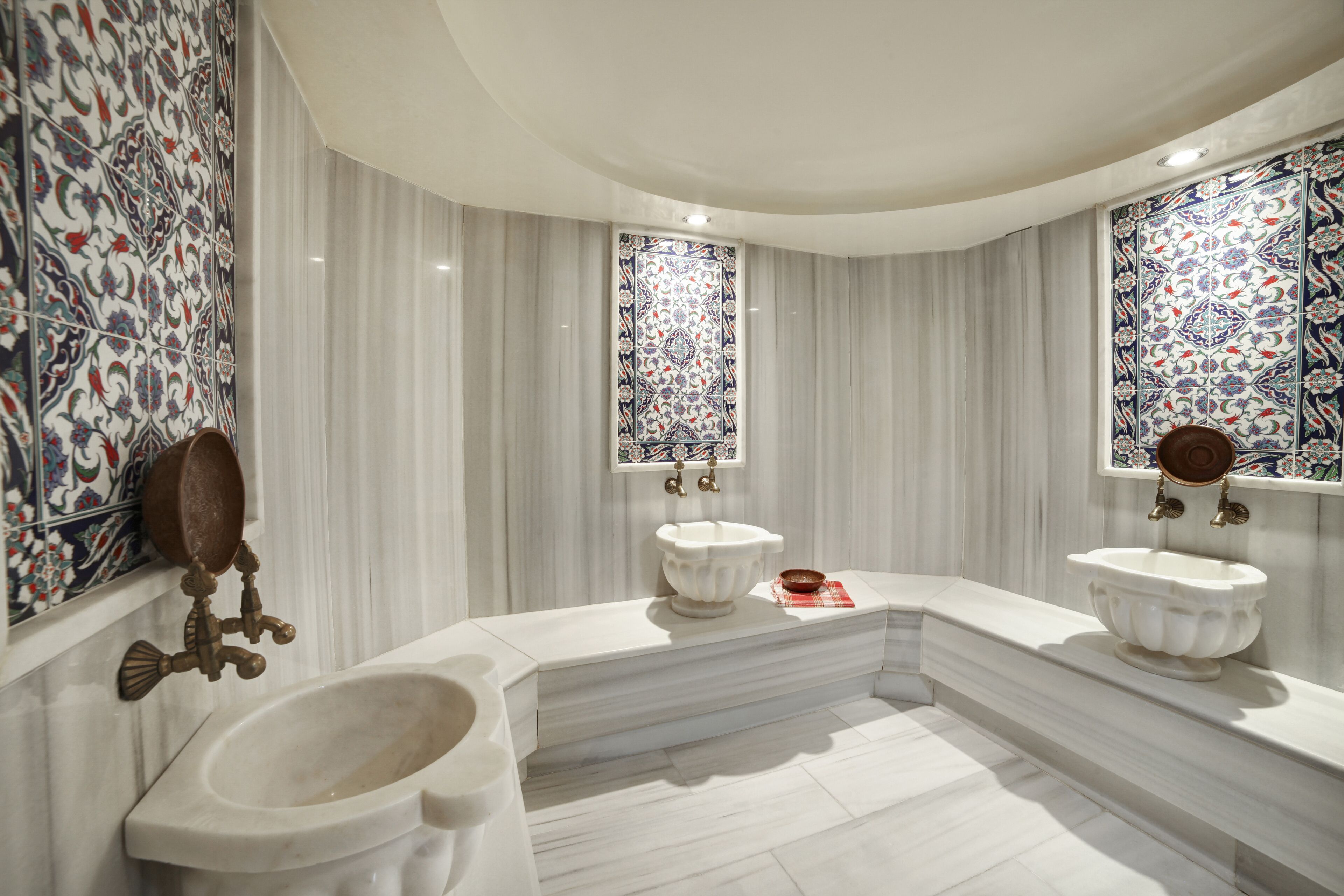 Een luxueuze badkamer met een groot marmeren wastafel, twee aparte wastafels en een toiletbril.