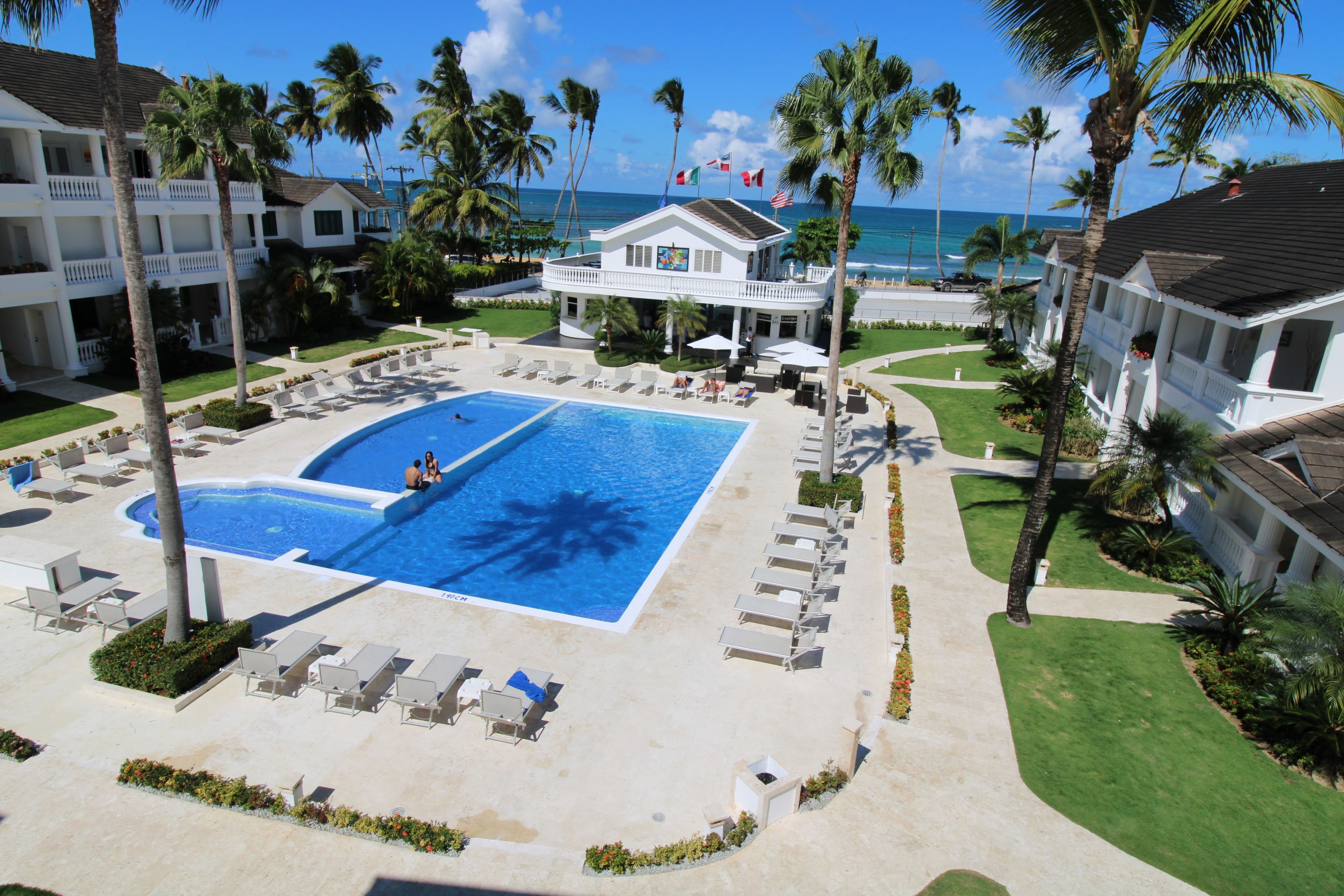A resort with a large pool, palm trees, and a view of the ocean.