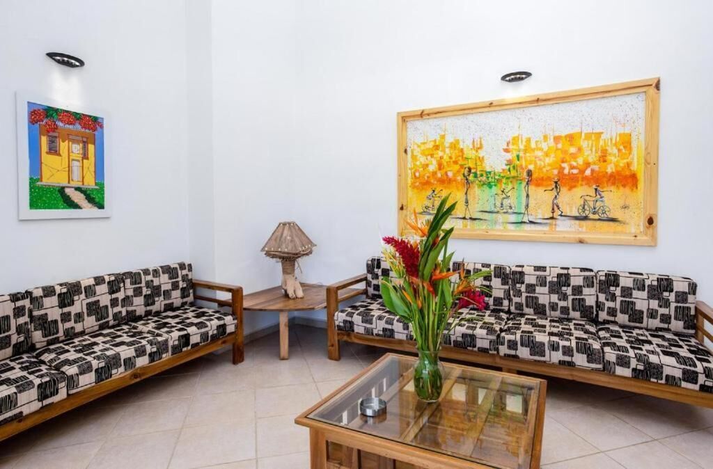 Una habitación con dos sofás estampados, una mesa de centro de cristal, una lámpara y un cuadro en la pared.