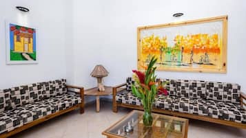 Una habitación con dos sofás estampados, una mesa de centro de cristal, una lámpara y un cuadro en la pared.