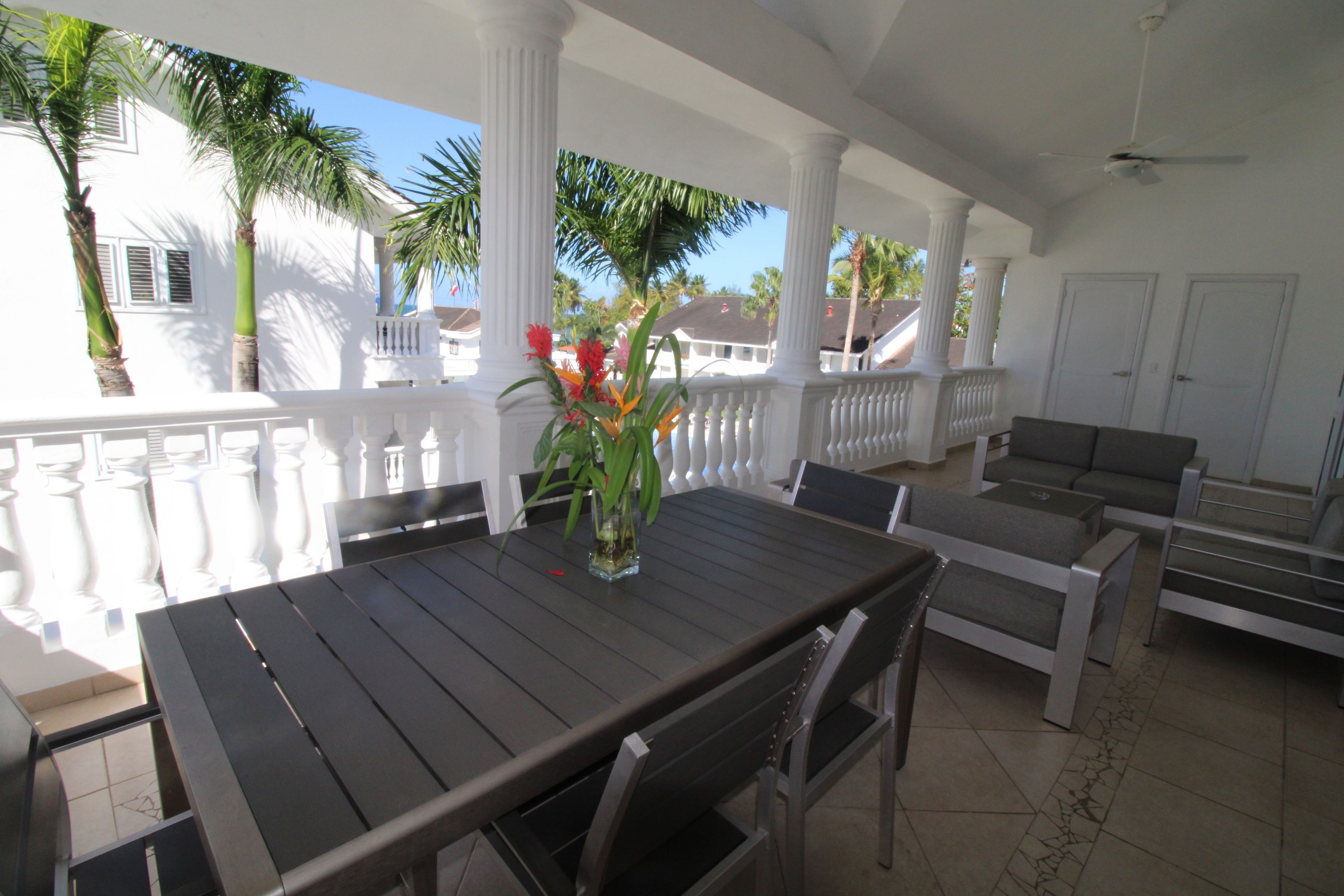 An outdoor patio with a dining table, chairs, and a sofa.