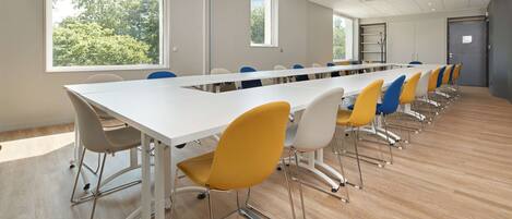 A conference room with a long table and chairs, large windows, and a door.