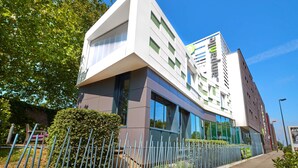 Un edificio moderno con un diseño arquitectónico distintivo, con amplios ventanales y una combinación de vidrio y metal.