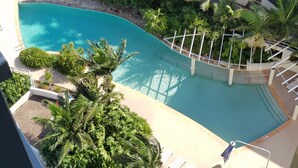 Une vue aérienne d’une piscine entourée d’une végétation luxuriante et de palmiers.