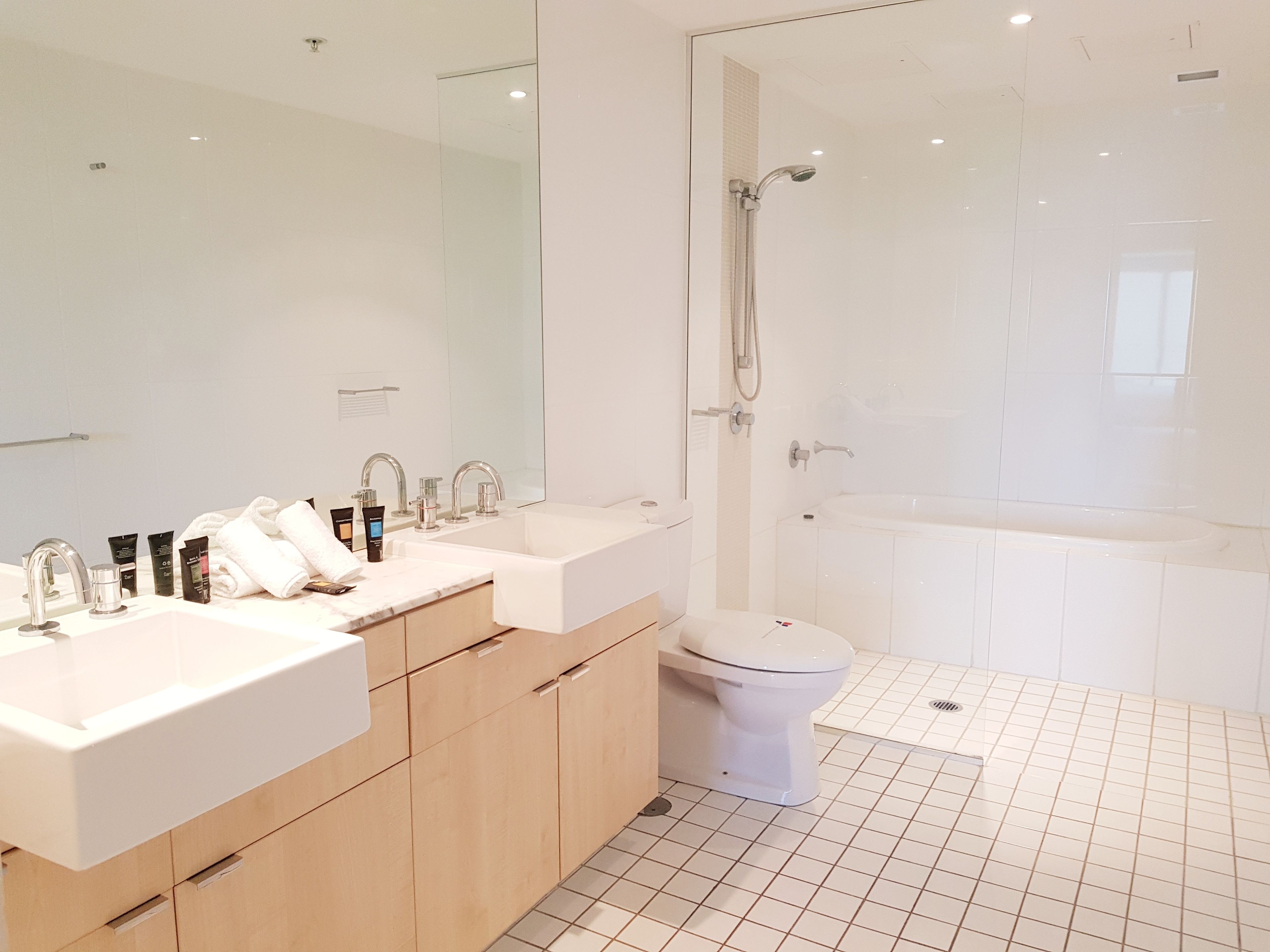 A modern bathroom with a double sink vanity, a toilet, and a shower area.