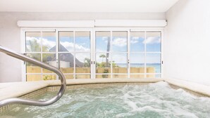 Een hottub met een metalen leuning, een betegelde vloer en uitzicht op een huis door een horreken.