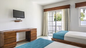 Un dormitorio con un escritorio de madera, una cama, un televisor y vistas al exterior.
