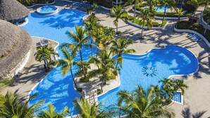 Een resort met diverse zwembaden, palmbomen en ligbedden.