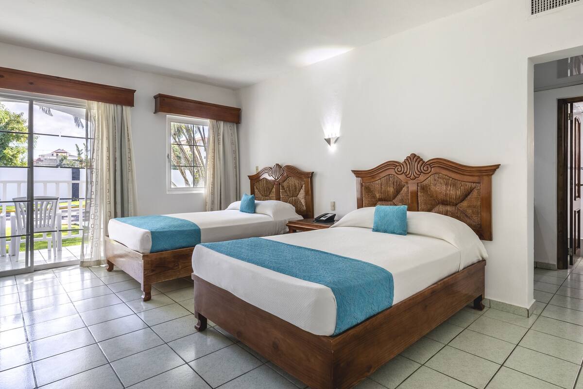 Een hotelkamer met twee bedden, een balkon en uitzicht.