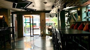 A modern interior with a bar area, seating, and a view of the street. - The Fusion Suites (Bangkok)