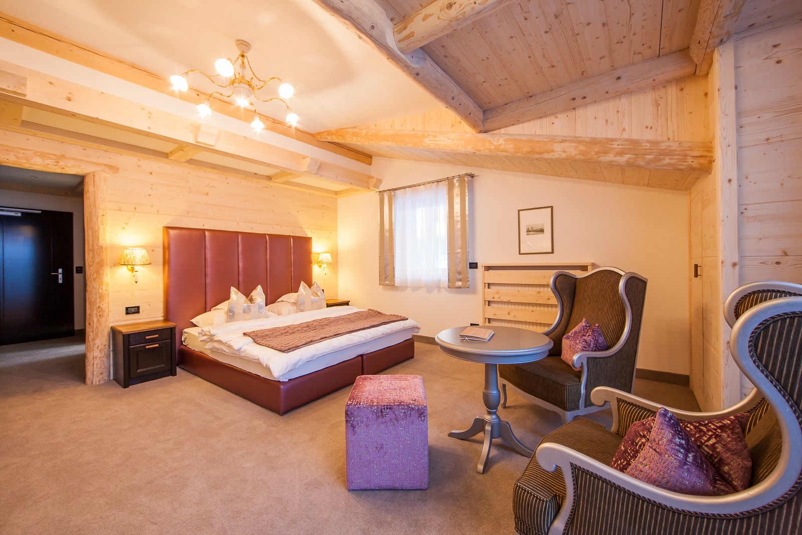 Ein gemütliches Schlafzimmer mit einem großen Bett, einem Sessel, einem kleinen Tisch und einem Nachttisch.