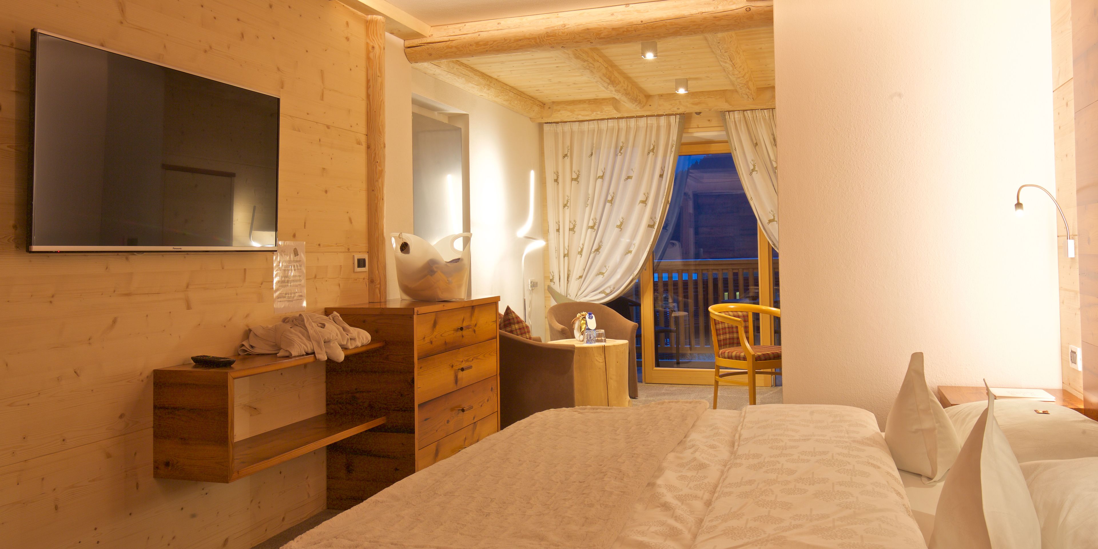 Ein Schlafzimmer mit einem Bett, einem Holzschrank und einem an der Wand befestigten Fernseher.