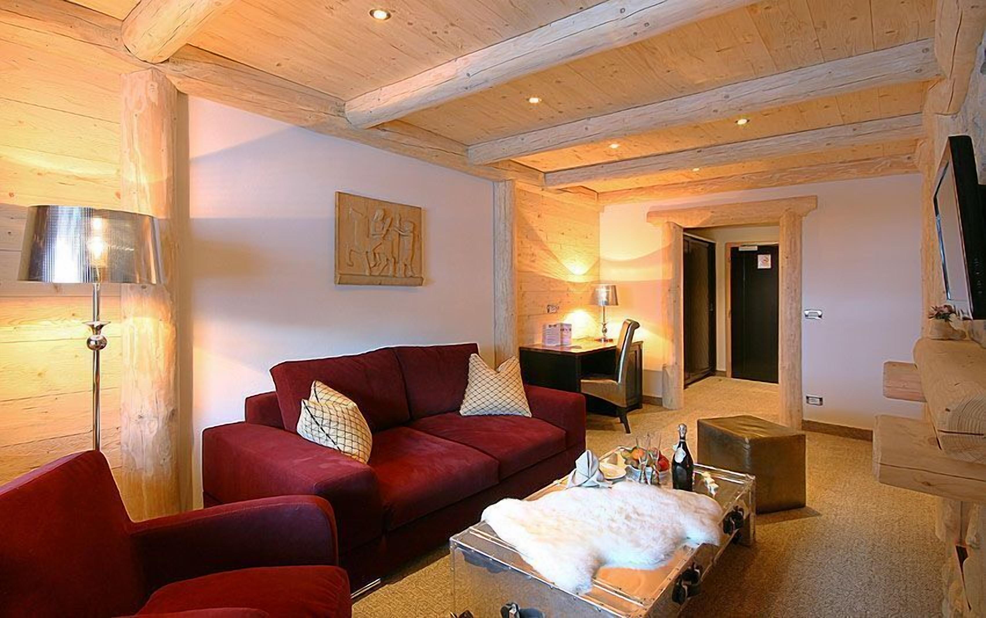 Una sala de estar acogedora con un sofá rojo, una mesa de centro de madera y una lámpara.