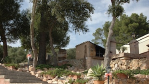 A stone staircase leading up to a rustic building with a stone wall and potted plants. - Finca Son Samà (Llucmajor)