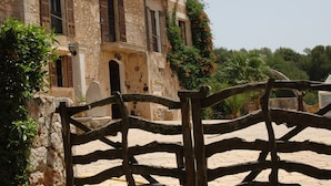 A stone building with wooden shutters, a balcony, and a sign that reads "Conza." - Finca Son Samà (Llucmajor)