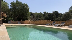 A clear swimming pool with lounge chairs and a stone wall. - Finca Son Samà (Llucmajor)