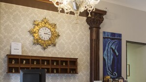 Un comptoir d’accueil orné d’une horloge, d’un lustre et d’un tableau accroché au mur.